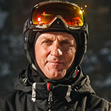 A photo of David, one of the personas for Powder. David is a male who looks to be in his sixties or early seventies, and he has a black helmet and orange ski goggles on his head.